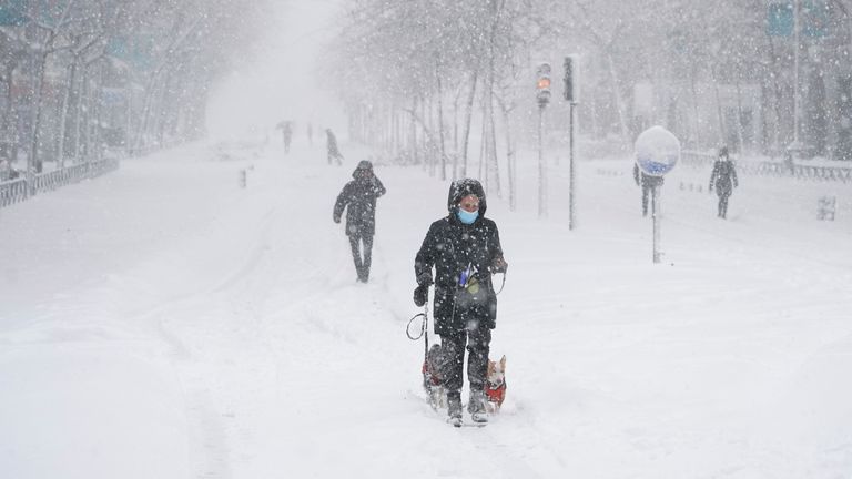 People walk and ski in the city center during heavy snowfall in Madrid