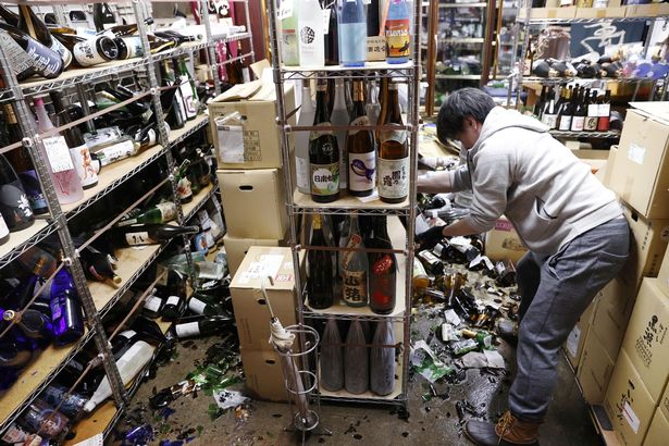 A worker cleans broken bottles in a liquor store after a strong earthquake in Fukushima
