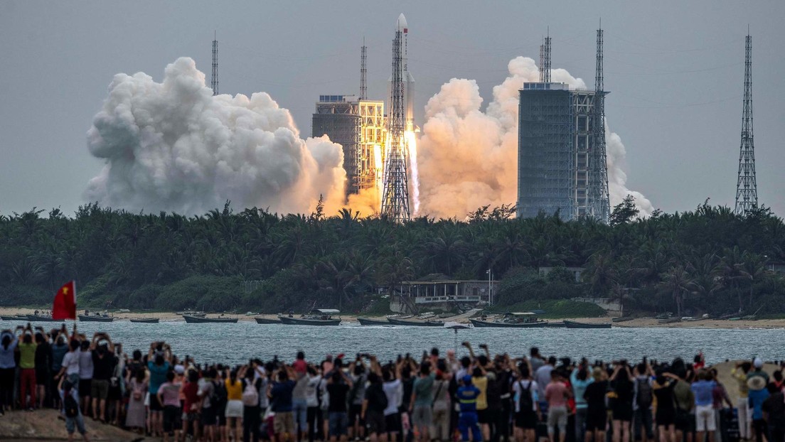 Dozens of people watch from a beach as the Long March-5BY2 rocket launches from the Wenchang Space Launch Center in Hainan, China.  April 29, 2021.
