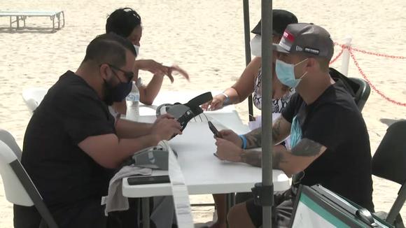Latin American tourists get vaccinated against COVID-19 on a beach in Miami Beach