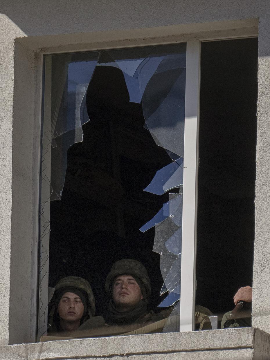 Ukrainian soldiers look through a broken window after an explosion at a military facility in the Ukrainian capital.