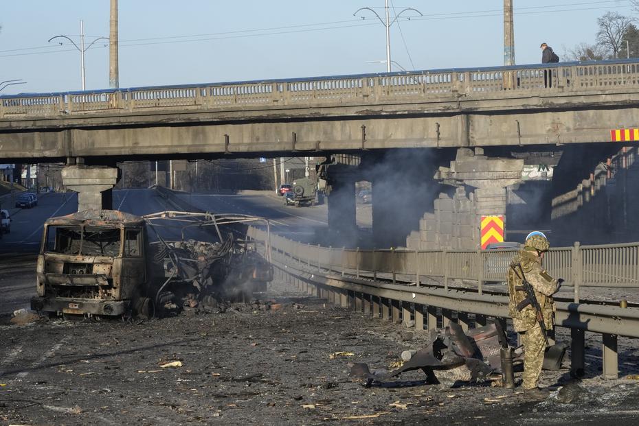 A Ukrainian soldier investigates the wreckage of a burned-out military truck on a street in Kiev, Ukraine.