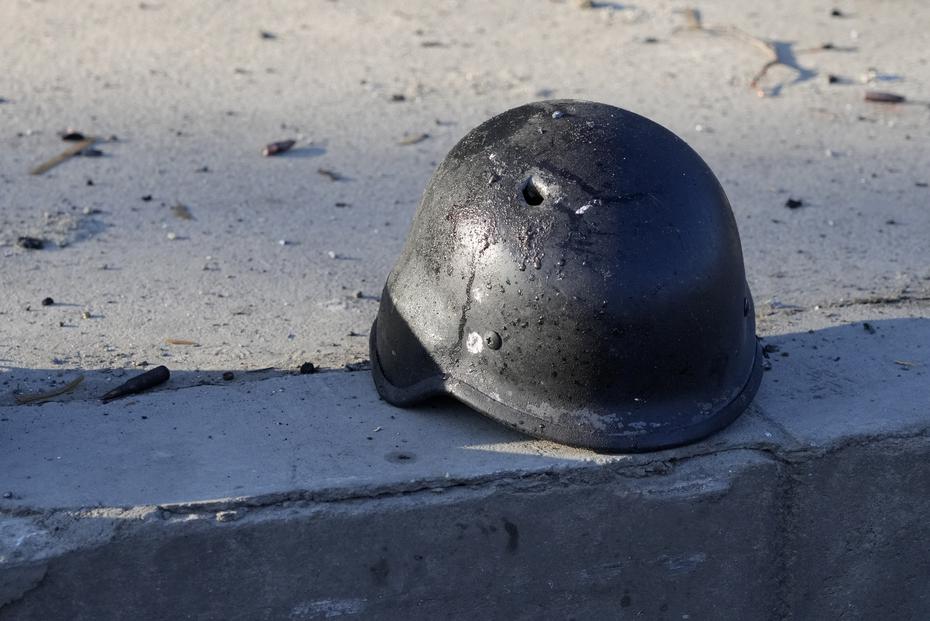 A soldier's helmet punctured by a bullet, near the wreckage of charred military trucks, on a street in Kiev, Ukraine.
