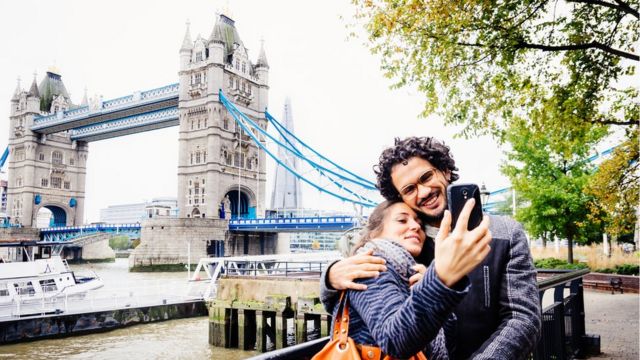 Couple taking a picture in front of Tower Bridge in London