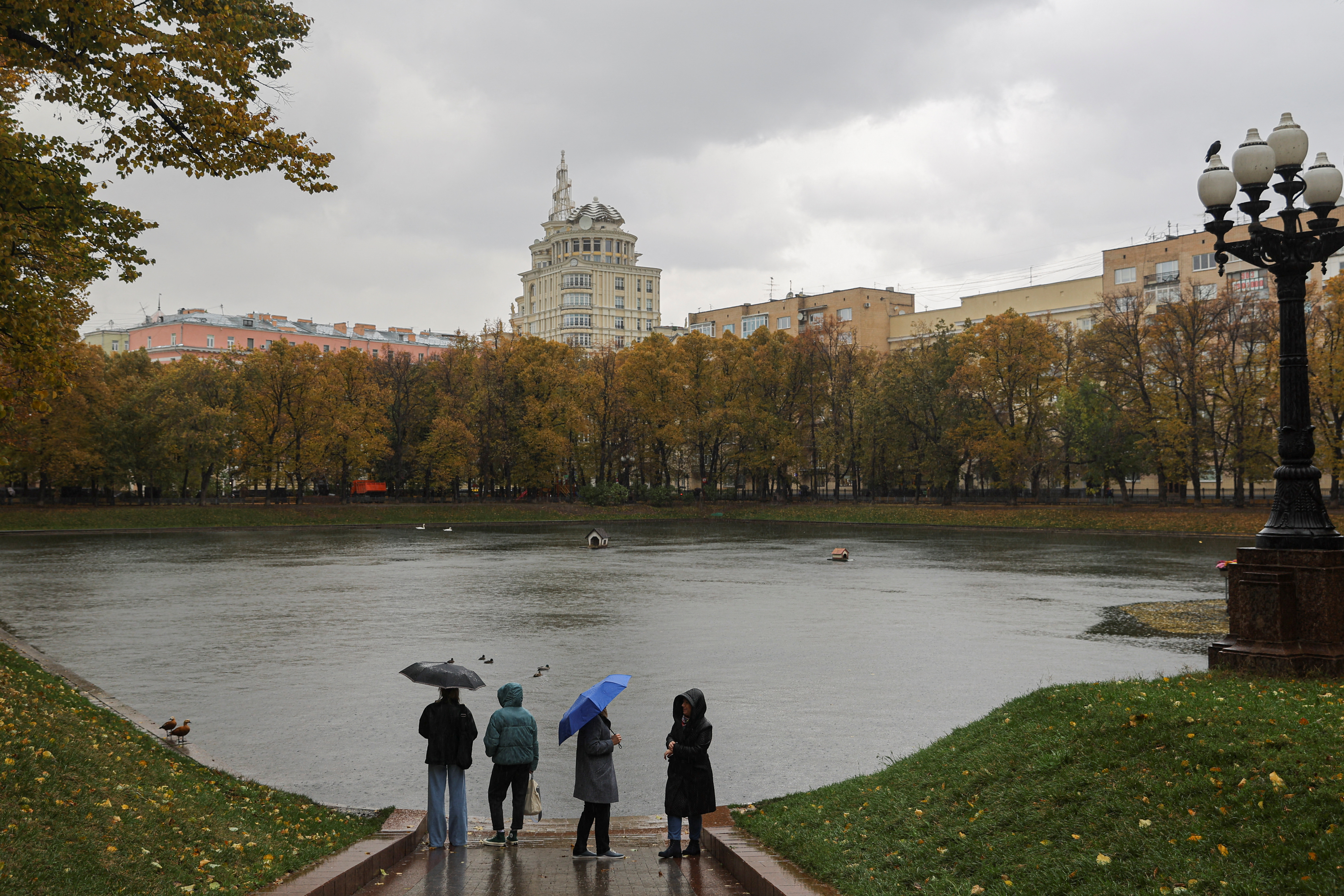 Women next to a pond on a rainy day in Moscow, Russia, October 4, 2022. (REUTERS/Evgenia Novozhenina)